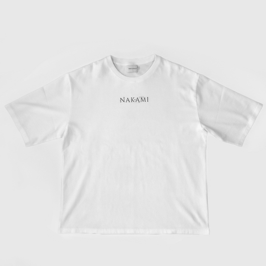 Das weiße Infinity Shirt von Nakami liegt auf dem Boden. Auf dem Shirt ist das Nakami Logo abgedruckt.