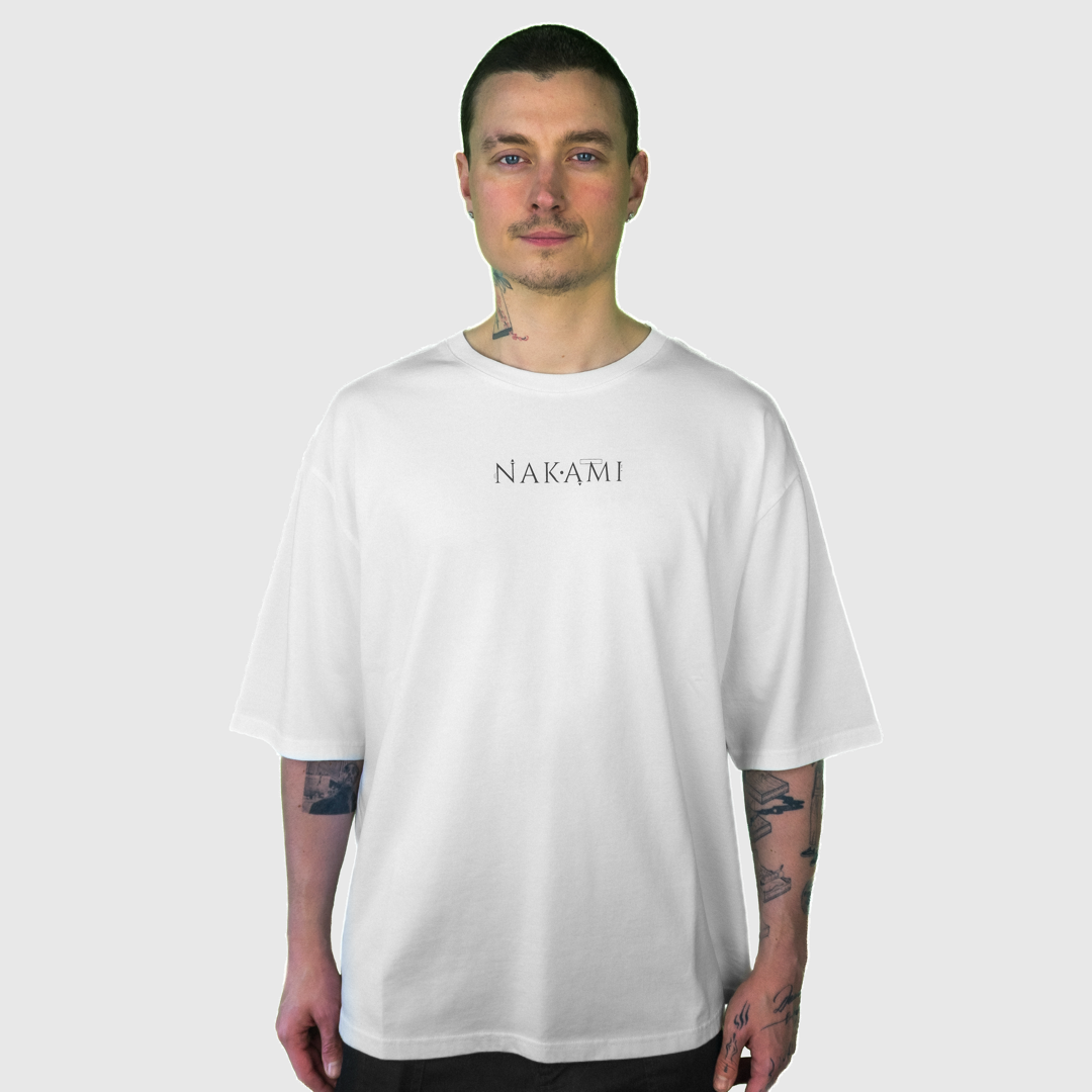 Ein Mann mit kurzen Haaren trägt das weiße Infinity Shirt von Nakami. Das Model schaut in die Kamera.